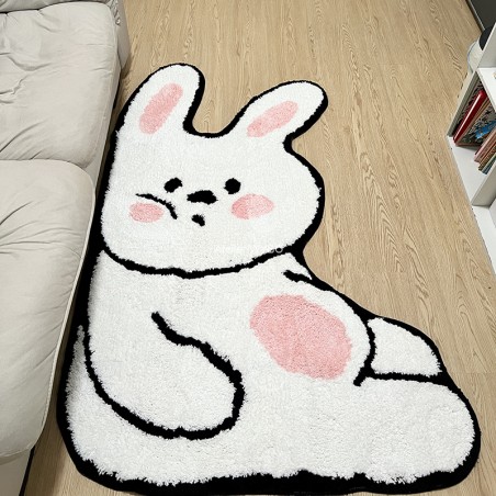 Tapis blanc rigolo en forme de lapin devant un canapé blanc.