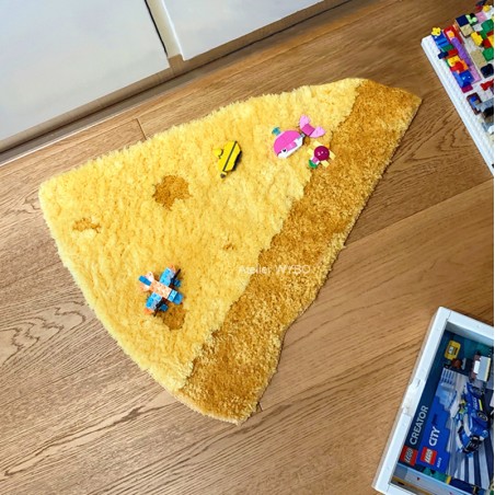 Tapis trompe-l’œil une part de fromage forme triangulaire.