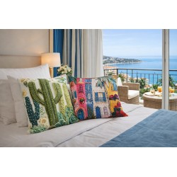 Coussins plantes grasses et maison traditionnelle méditterraniènne sur un lit devant balcon panoramique.